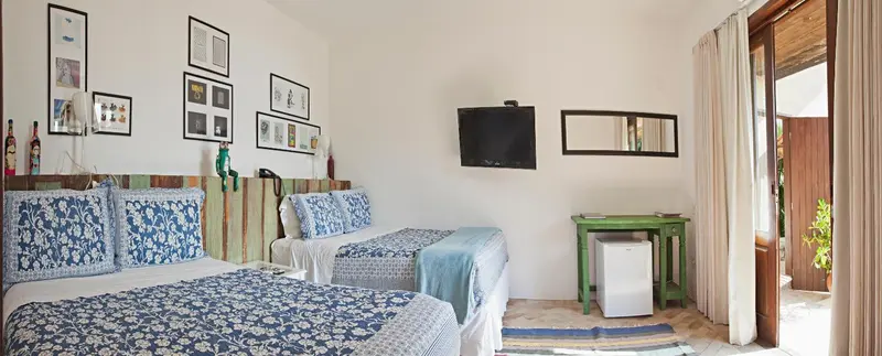 Chambre lumineuse avec deux lits et accès à une terrasse.