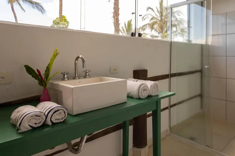Un lavabo blanc sur un meuble vert avec des serviettes enroulées.