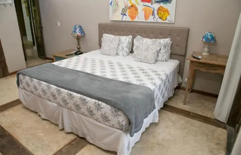 Une chambre avec un grand lit recouvert d'une courtepointe et de coussins.