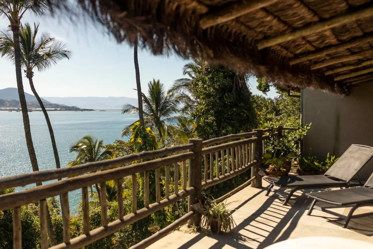Vue sur la mer depuis une terrasse ombragée avec des transats.