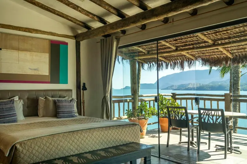 Une chambre lumineuse s'ouvre sur une terrasse avec vue sur la mer.