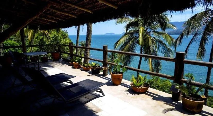 Terrasse ombragée avec transats donnant sur la mer et la végétation.