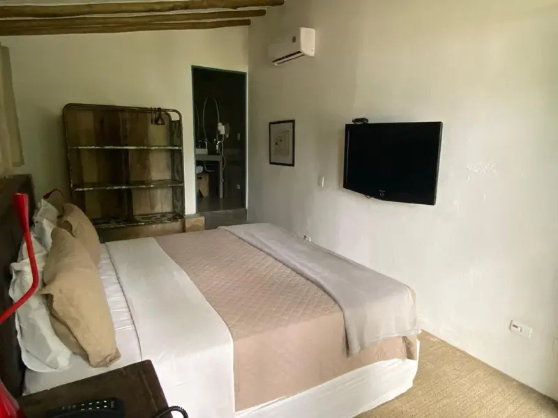 Une chambre lumineuse avec un grand lit et une télévision murale.