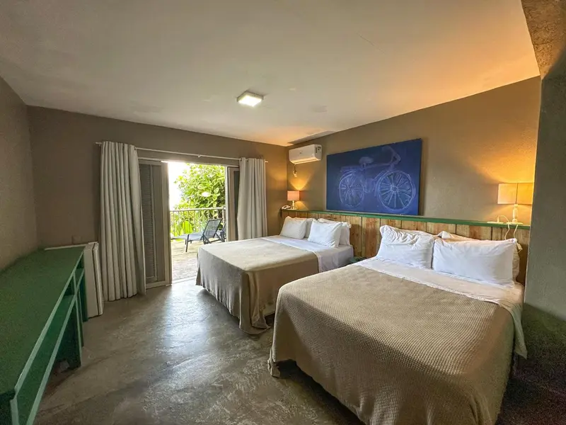Une chambre lumineuse avec deux lits et une vue sur une terrasse.