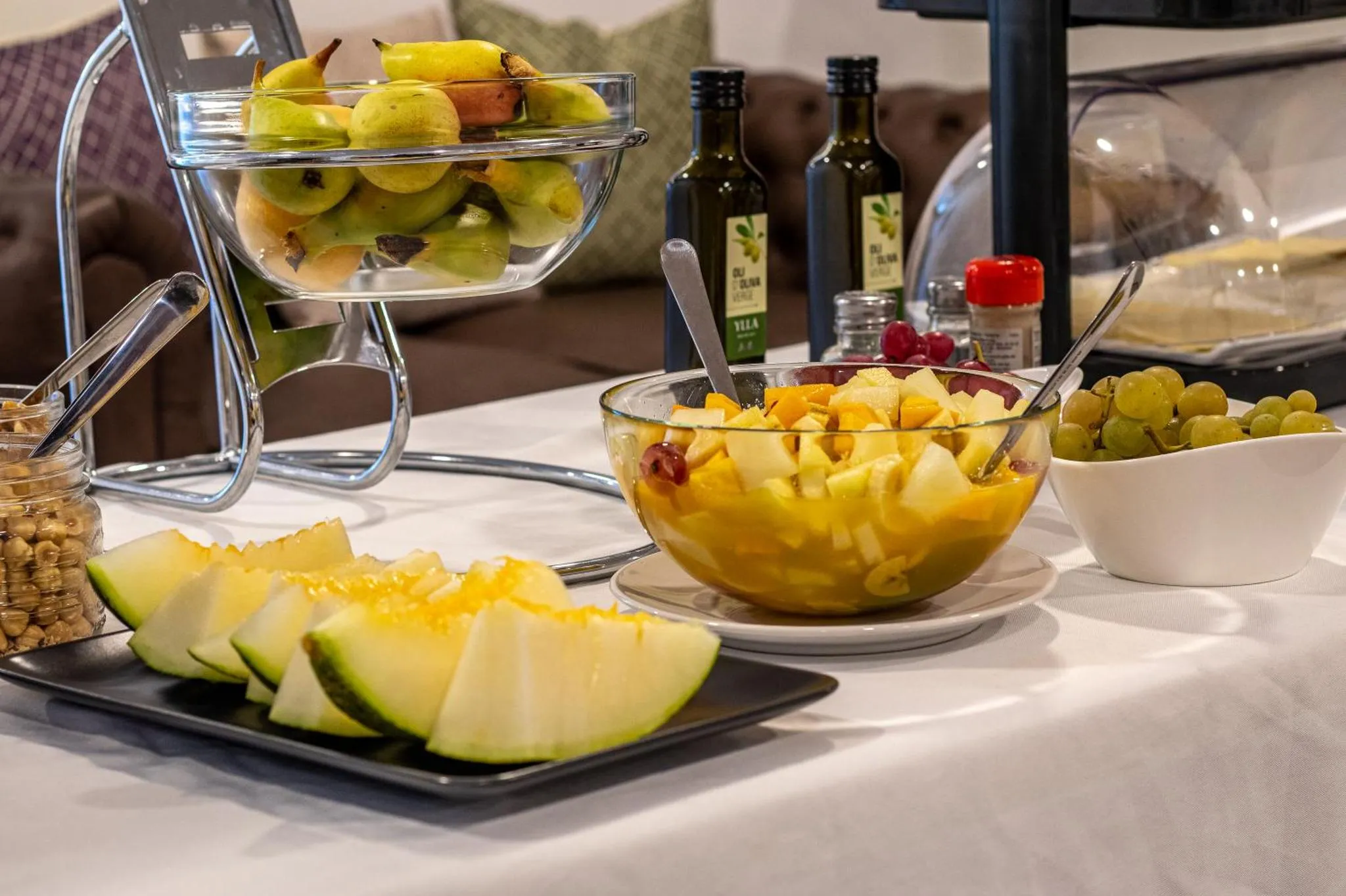 Une table blanche présente une variété de fruits frais coupés et disposés dans des récipients.