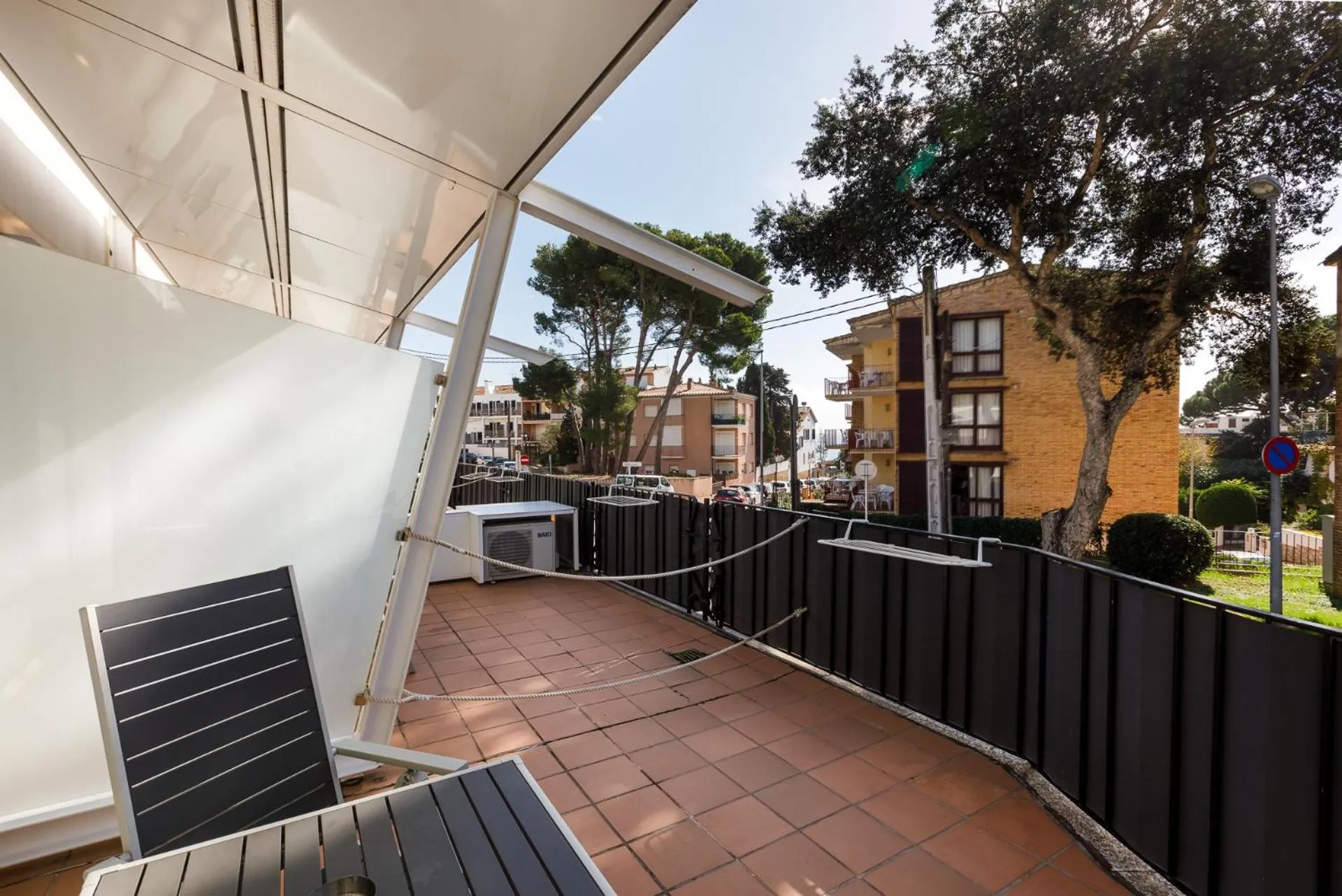Terrasse carrelée avec transats et vue sur des bâtiments.