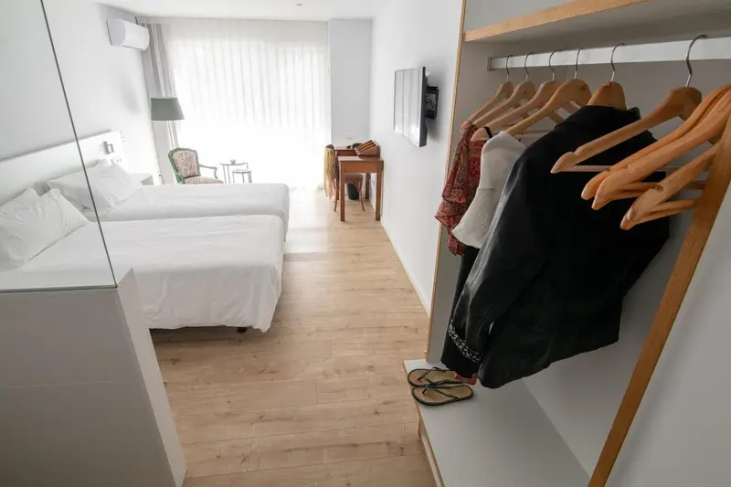 Une chambre lumineuse avec un lit blanc et un espace penderie.