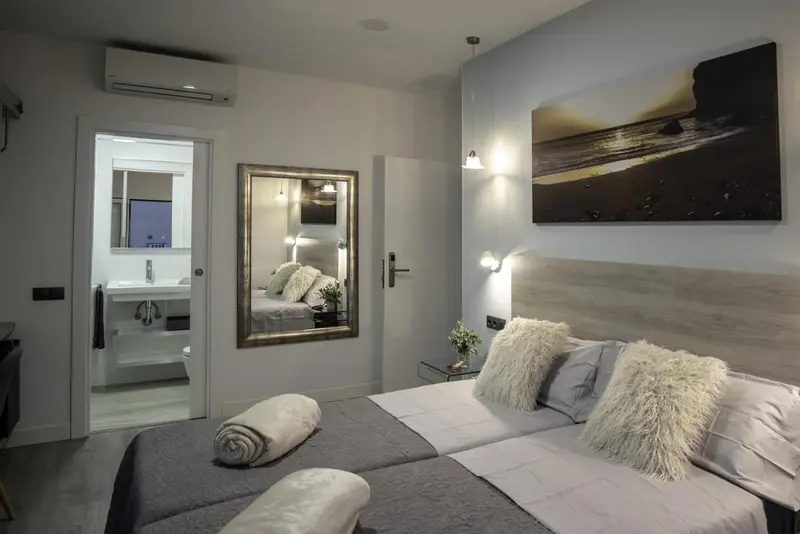 Une chambre lumineuse avec un grand lit et un miroir.