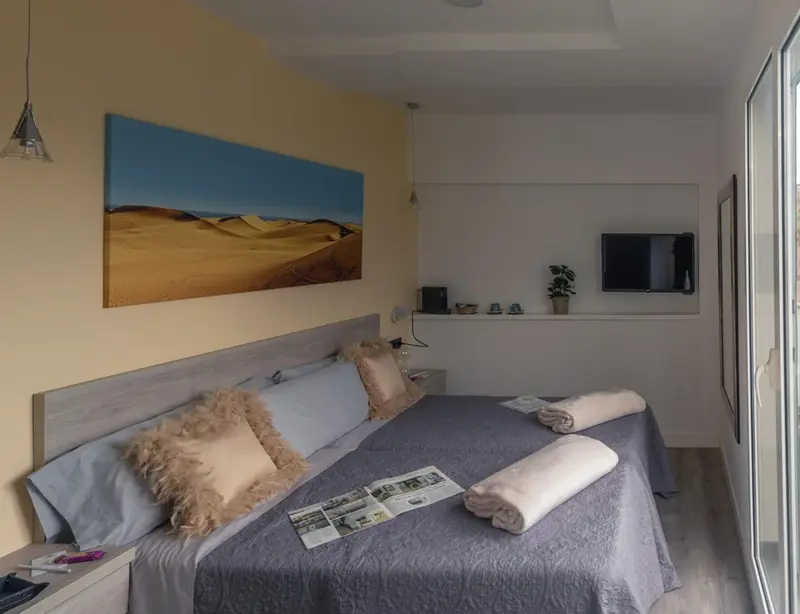 Une chambre lumineuse avec un grand lit et une décoration murale abstraite.