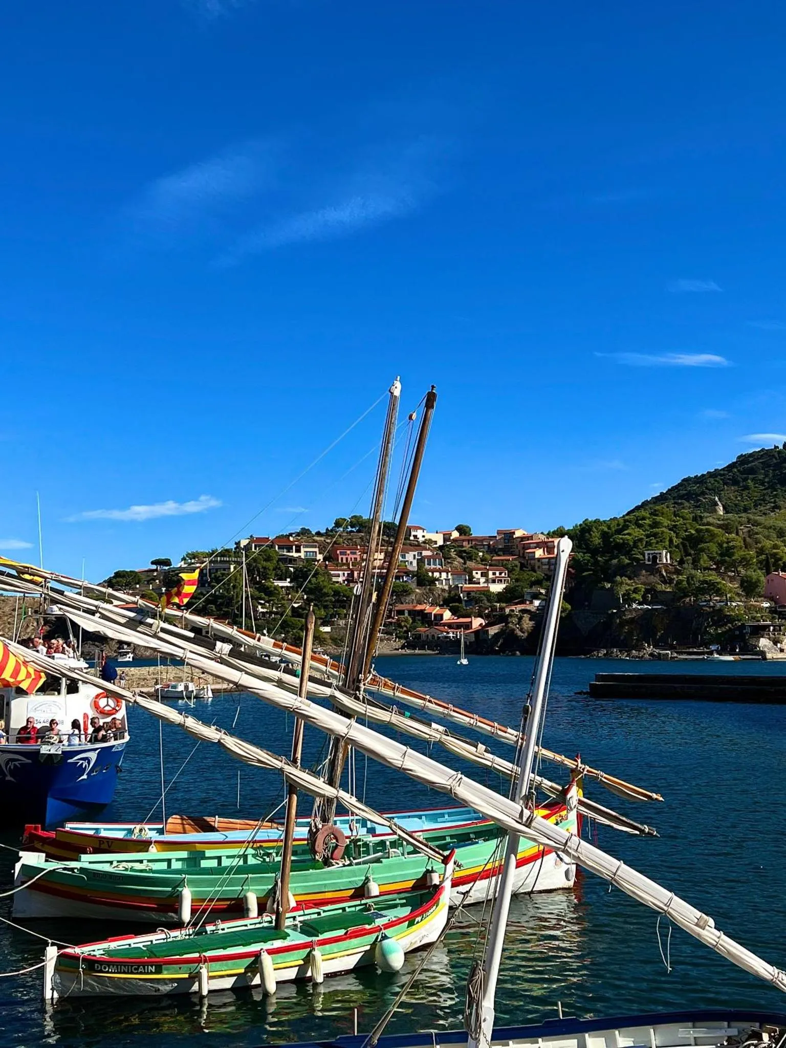 Bateaux traditionnels amarrés dans un port de village ensoleillé.