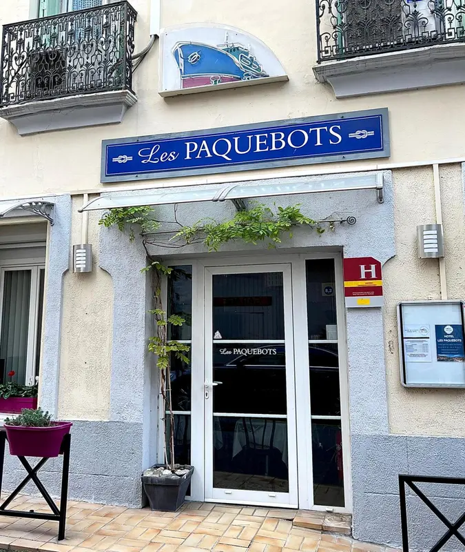 Façade d'un bâtiment avec une entrée et un panneau indiquant un nom.