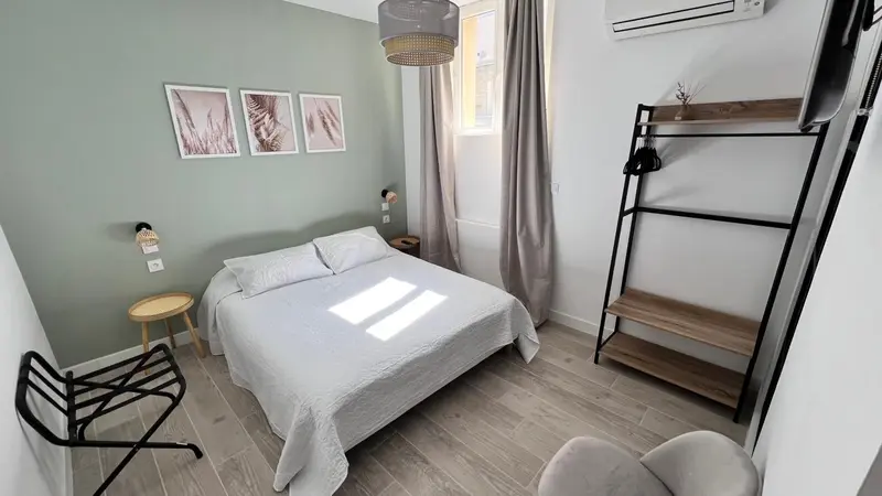 Une chambre lumineuse avec un lit double et un portant à vêtements.