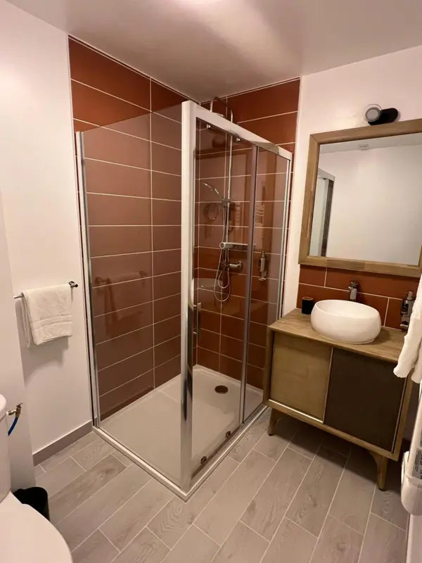 Une salle de bain moderne avec douche à l'italienne et vasque.