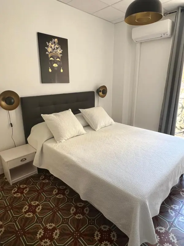 Une chambre lumineuse avec un grand lit recouvert d'une courtepointe blanche.