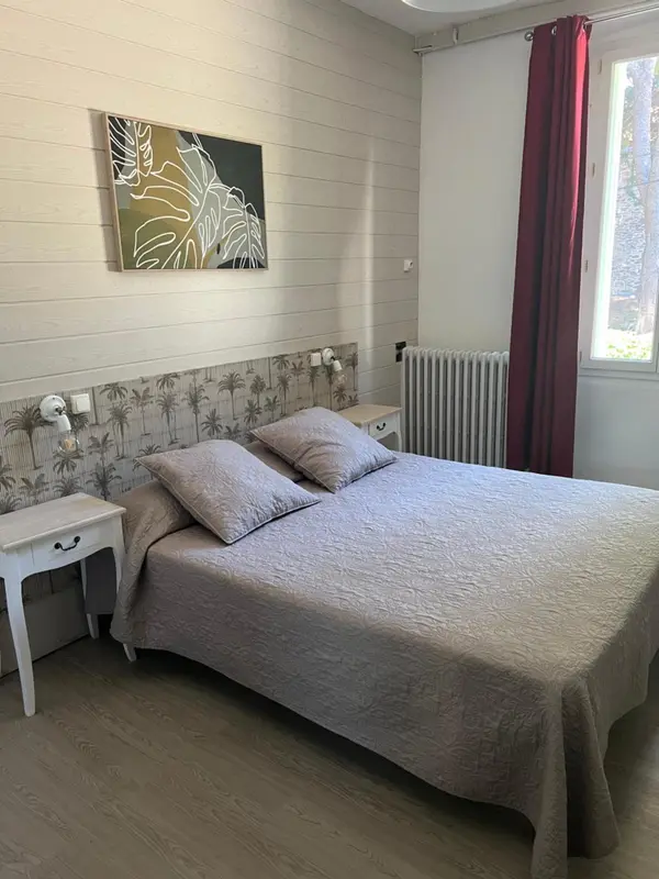 Une chambre lumineuse avec un grand lit recouvert d'une couette grise.