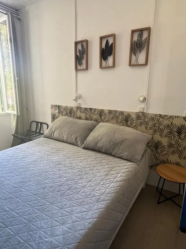 Une chambre lumineuse avec un grand lit recouvert d'une courtepointe.