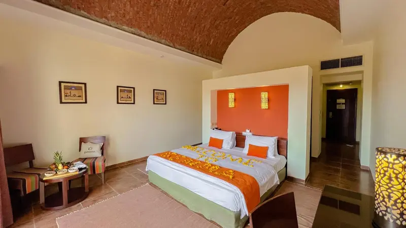 Chambre lumineuse avec un lit décoré de fleurs et un coin salon.