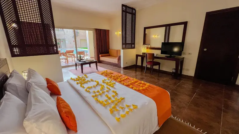 Une chambre lumineuse avec un lit décoré de fleurs et un coin salon.