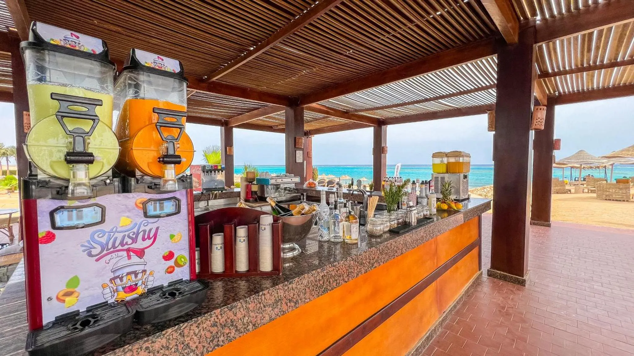 Un comptoir de bar extérieur propose des boissons fraîches avec vue sur la mer.