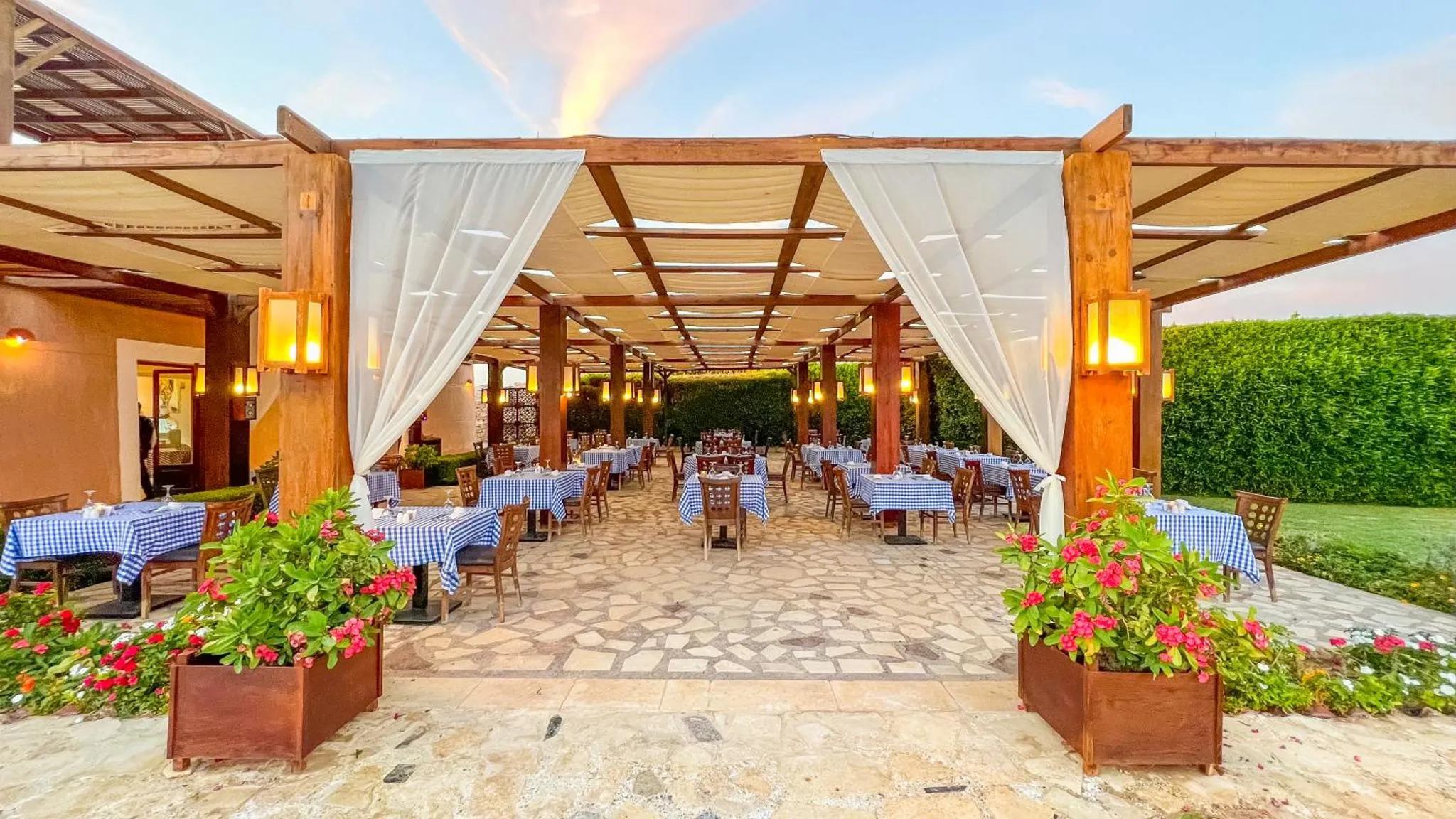 Terrasse ombragée avec tables dressées pour un repas en extérieur.