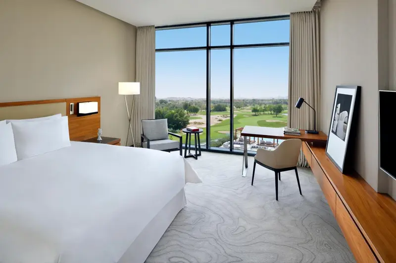 Chambre lumineuse avec un grand lit et une vue sur un terrain de golf.
