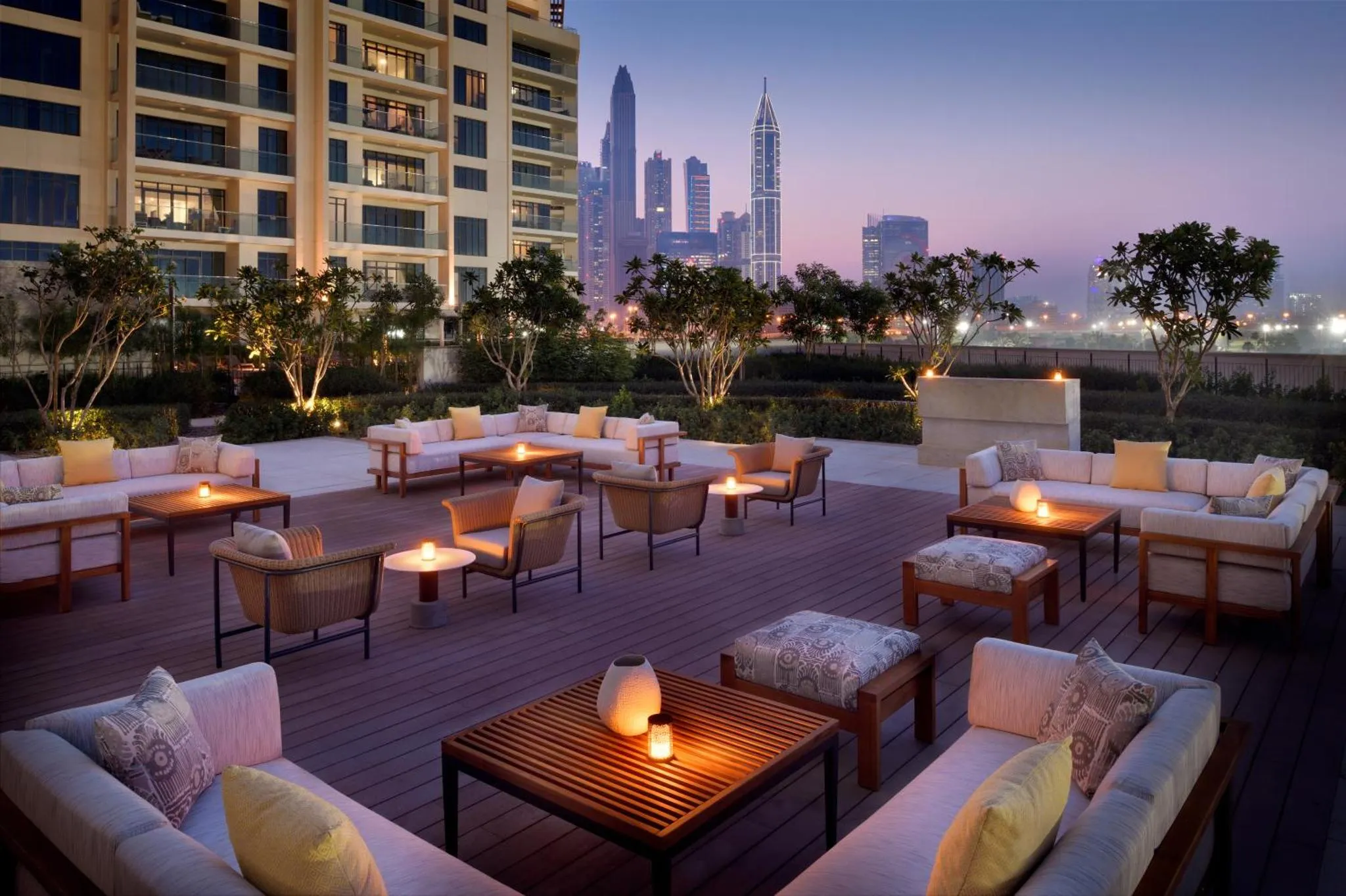 Terrasse aménagée avec des canapés et des tables basses au crépuscule.