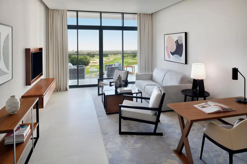 Un salon lumineux avec canapé et fauteuils, donnant sur un terrain de golf.