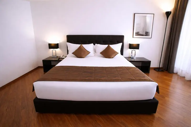 Une chambre lumineuse avec un grand lit recouvert d'une courtepointe.