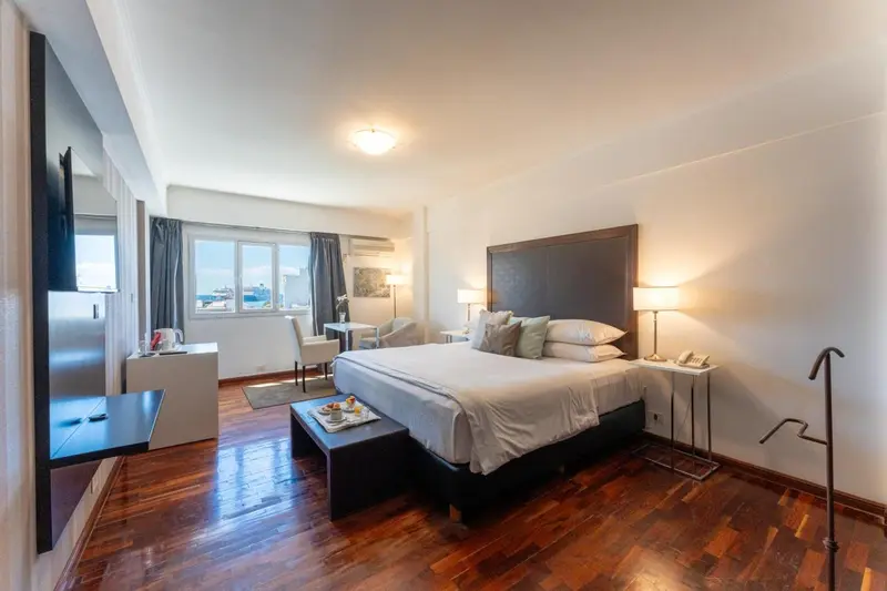 Chambre lumineuse avec un grand lit et une vue sur la mer.