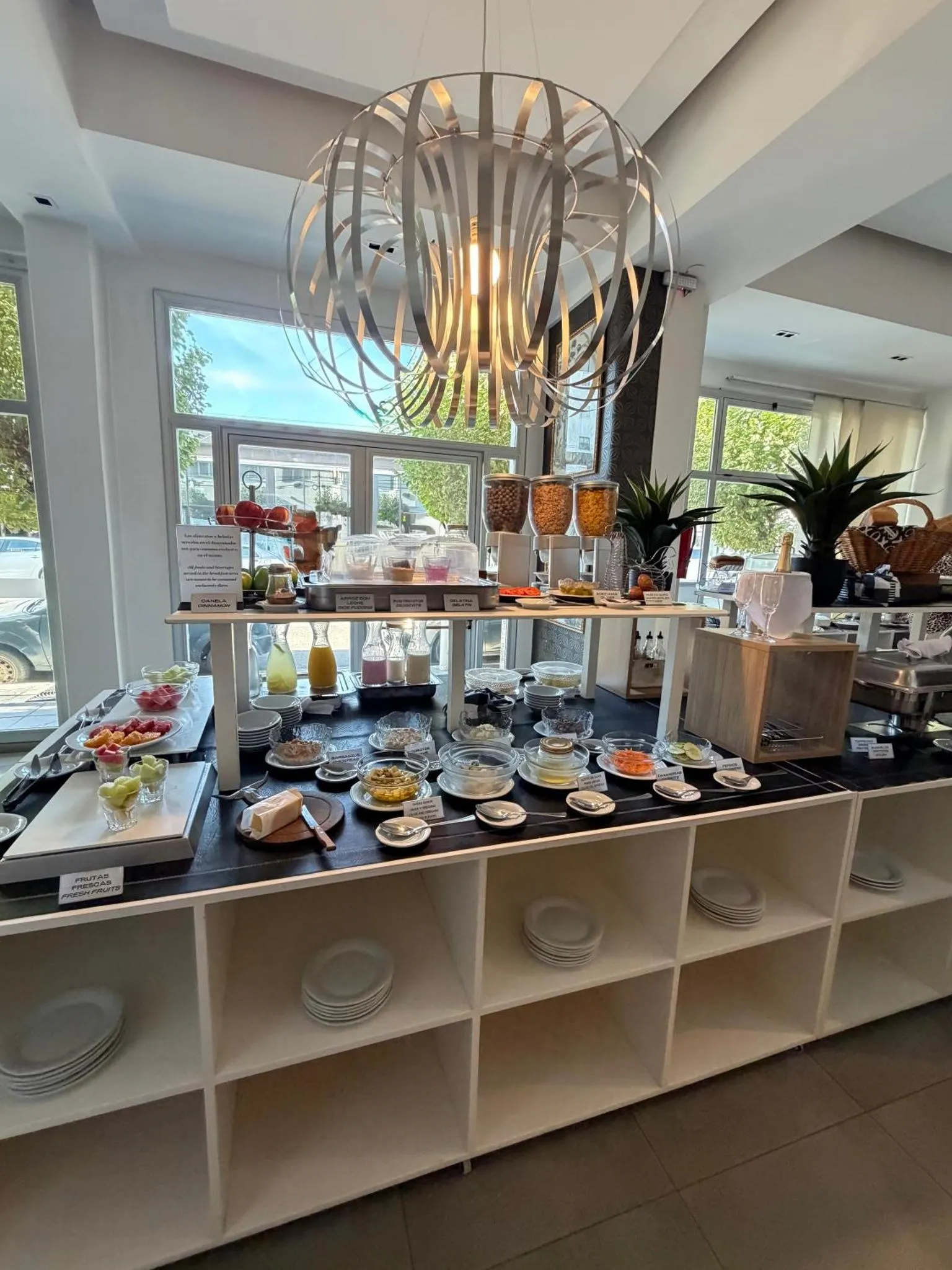 Un buffet propose des fruits, des pâtisseries et des boissons dans un espace lumineux.