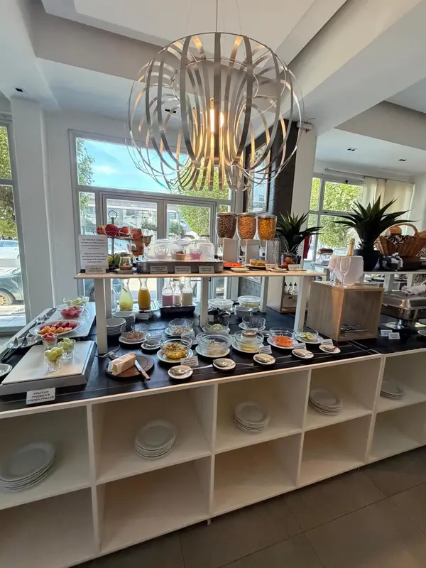 Un buffet propose des fruits, des pâtisseries et des boissons dans un espace lumineux.