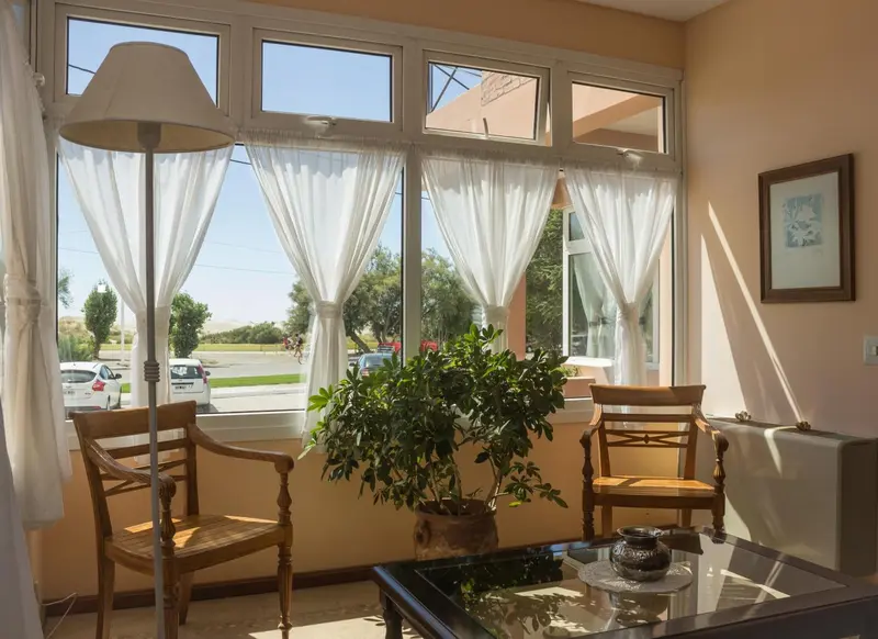 Espace lumineux avec deux fauteuils et une vue sur un paysage verdoyant.