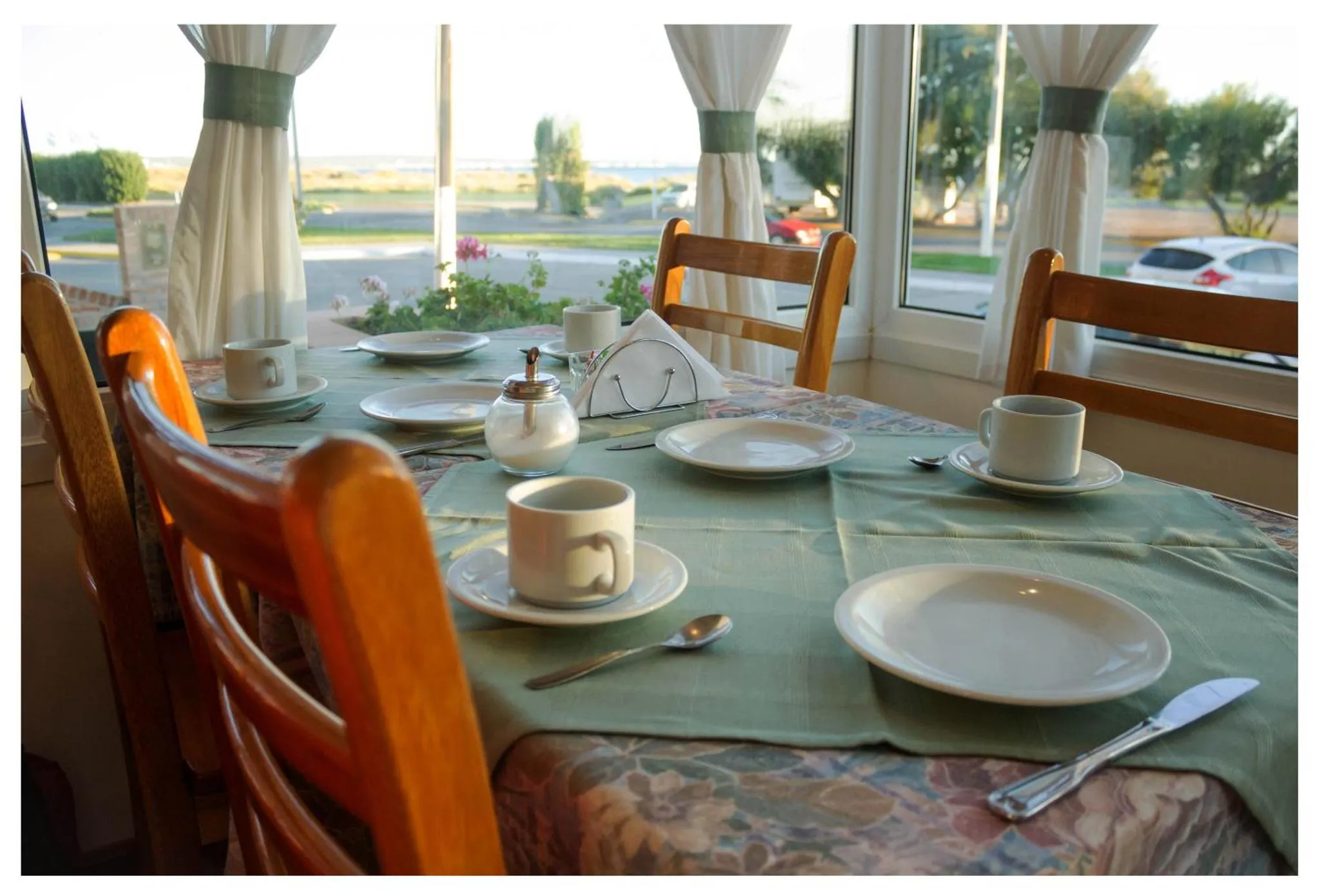 Une table est mise pour le petit-déjeuner avec des tasses, des assiettes et des couverts.