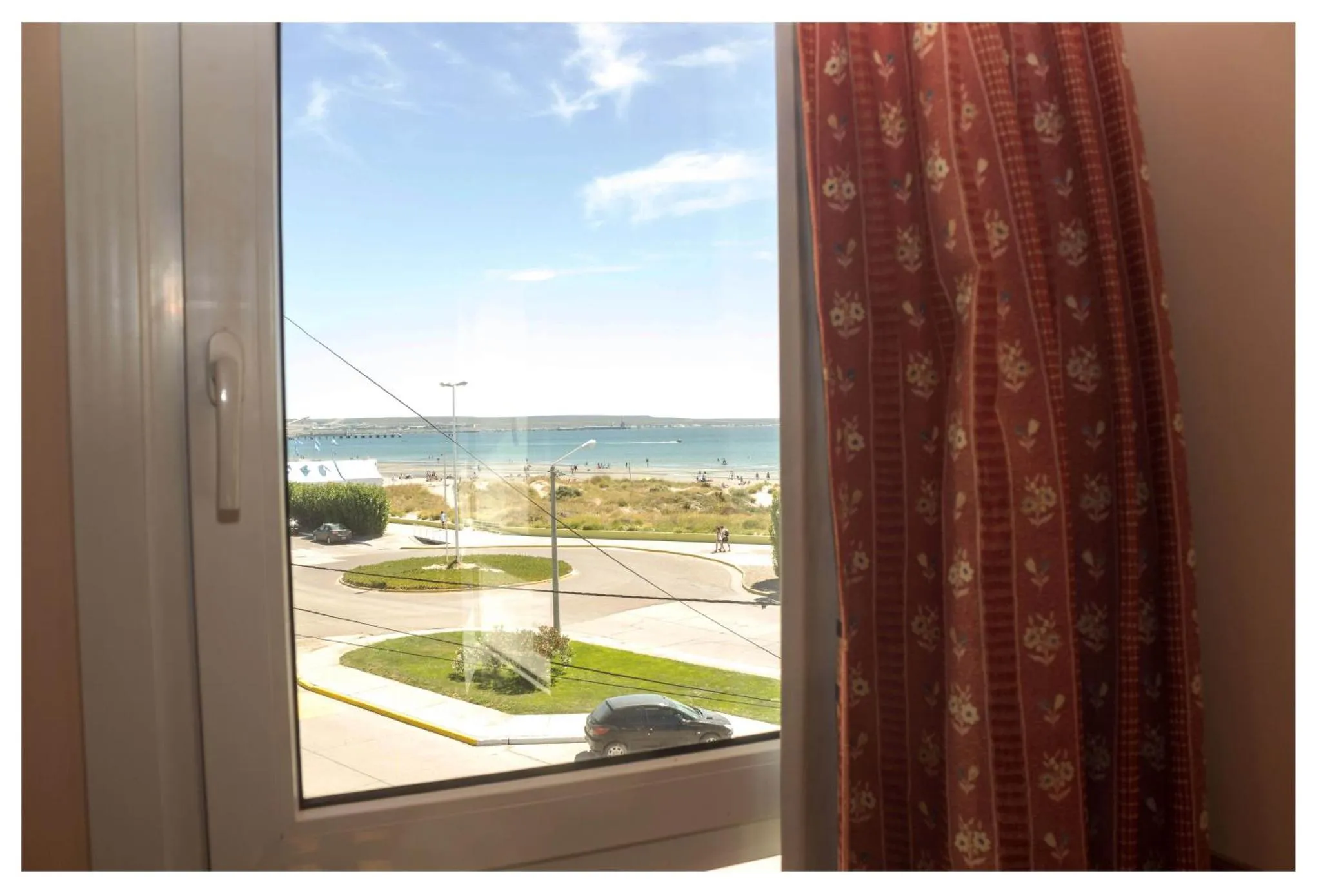 Vue sur la mer depuis une fenêtre avec un rideau.
