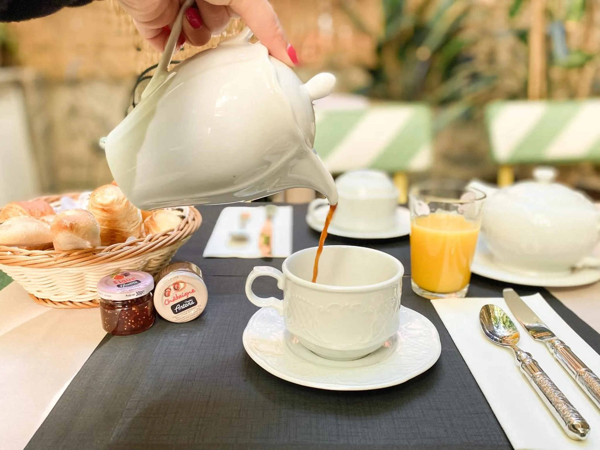 Une table est dressée avec un service à thé, des viennoiseries et des confitures.