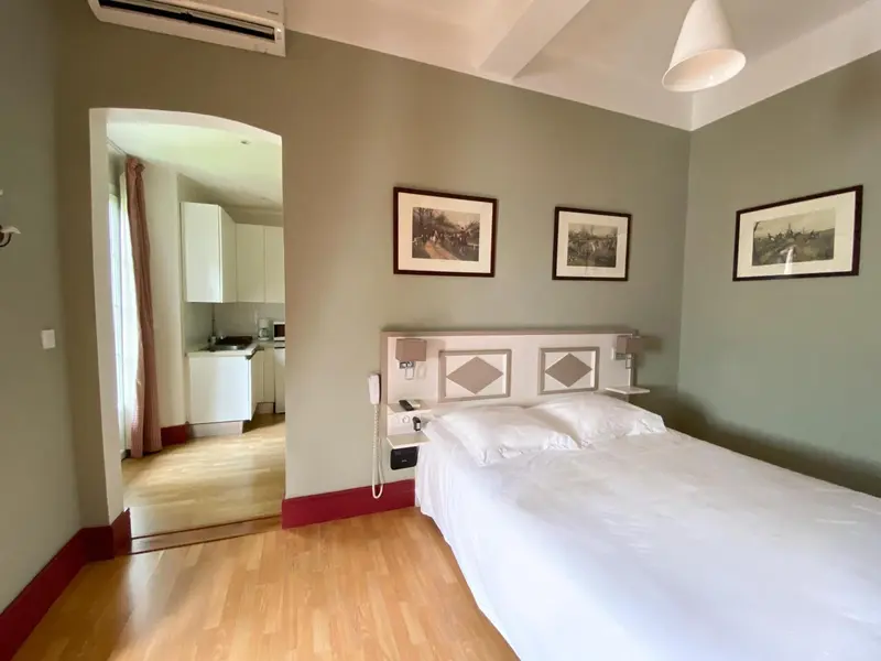 Une chambre lumineuse avec un lit blanc et des tableaux au mur.