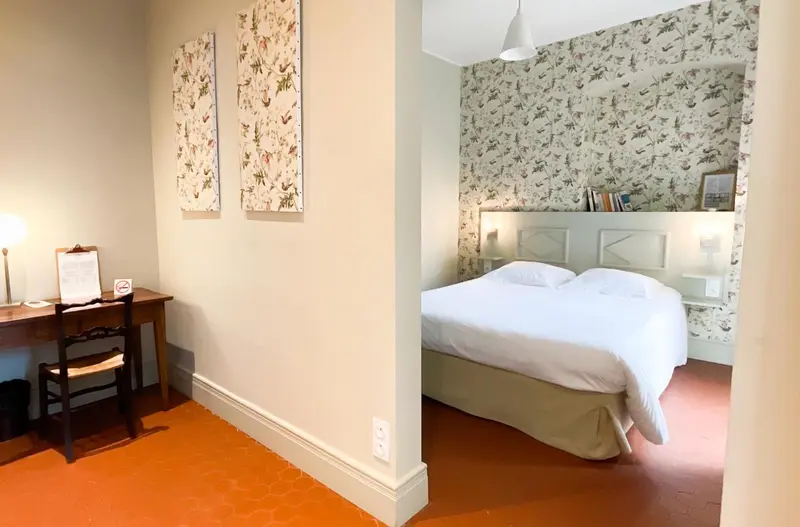 Une chambre lumineuse avec un lit fait et un bureau en bois.
