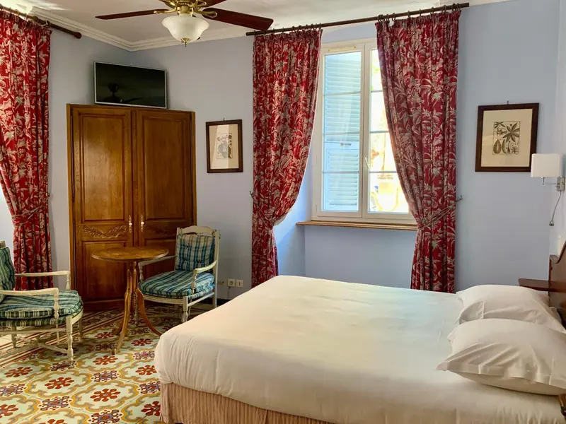 Une chambre lumineuse avec un lit, une fenêtre et un coin salon.