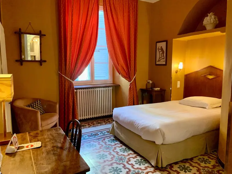 Une chambre à coucher lumineuse avec un lit fait et un coin salon.