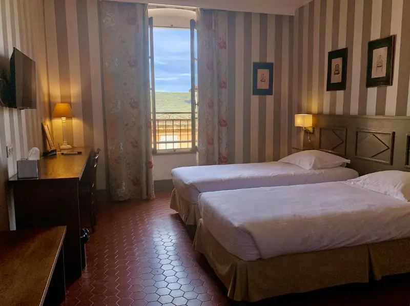 Une chambre lumineuse avec deux lits simples et vue sur un paysage.