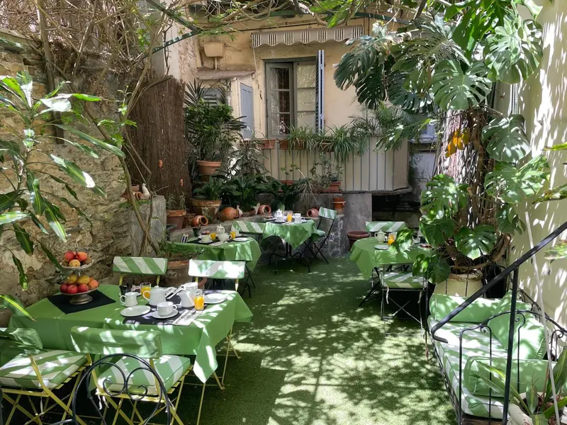 Une cour intérieure verdoyante avec des tables dressées pour le petit-déjeuner.