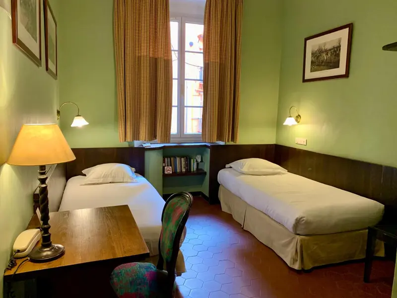 Une chambre lumineuse avec deux lits simples et une fenêtre.