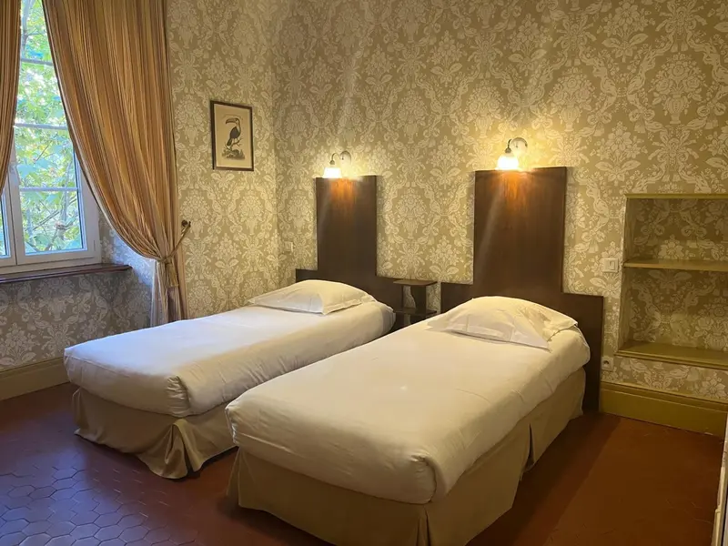 Chambre avec deux lits simples et décoration florale.