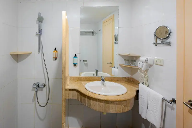 Une salle de bain claire avec douche et lavabo intégré dans un meuble.