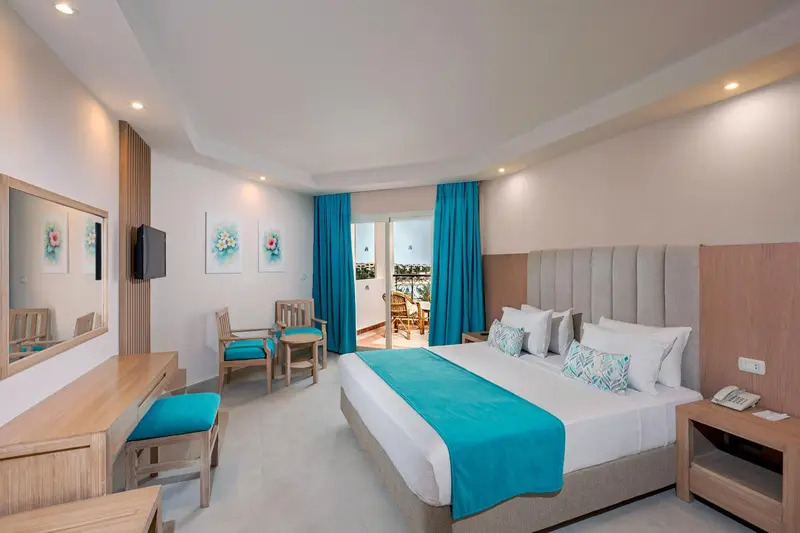 Chambre lumineuse avec un grand lit et un coin salon.
