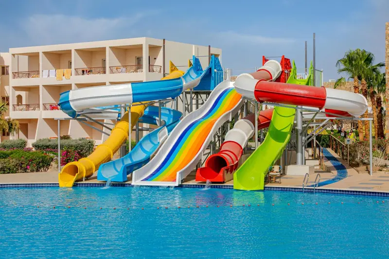 Toboggans aquatiques colorés se déversant dans une piscine ensoleillée.
