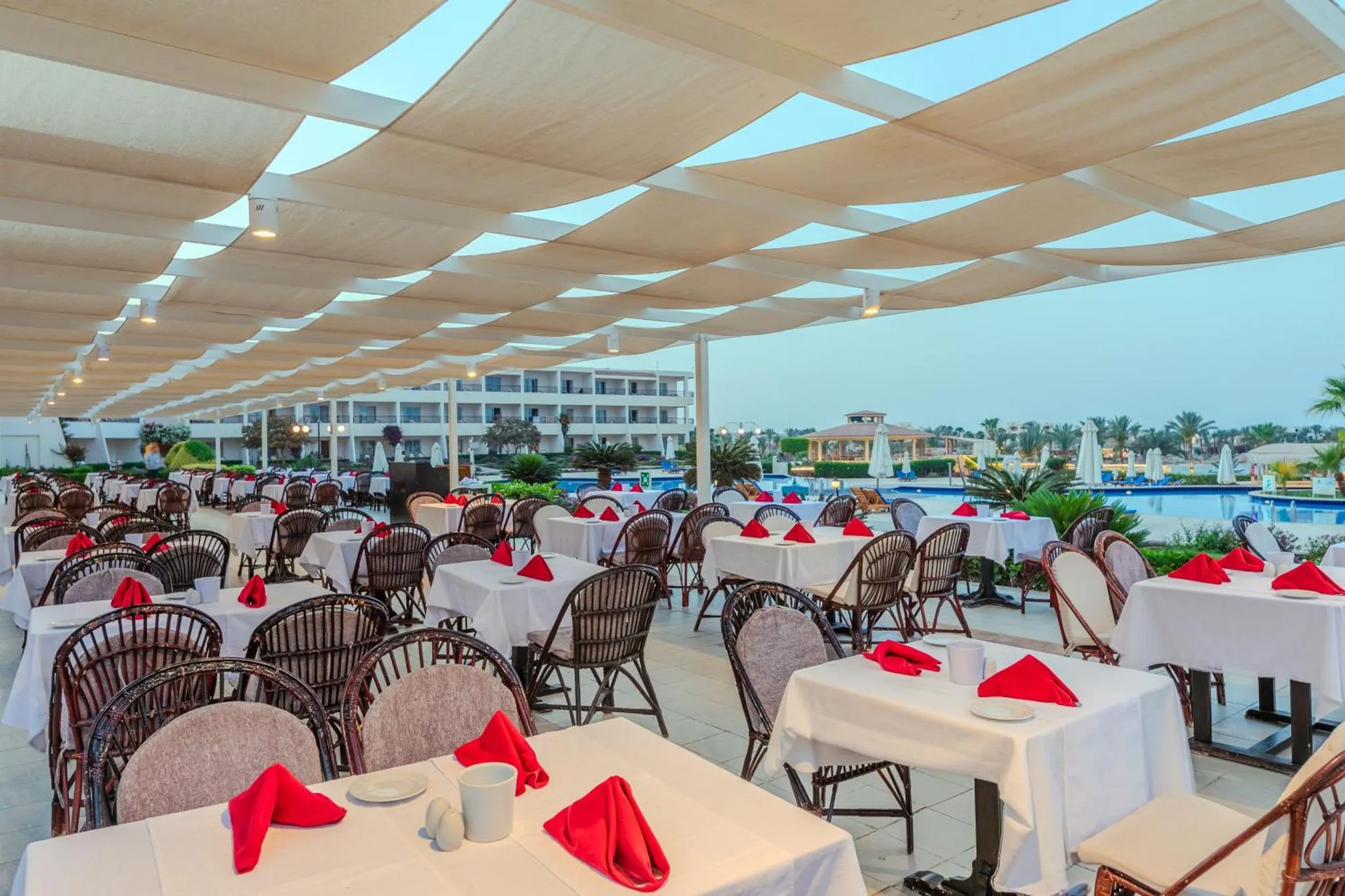 Terrasse ombragée avec tables dressées pour un repas en extérieur.
