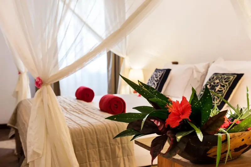 Un lit recouvert de moustiquaire dans une chambre décorée de fleurs.