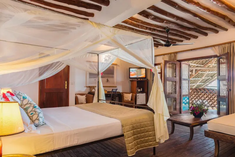 Une chambre lumineuse avec un lit à baldaquin et une vue sur l'extérieur.