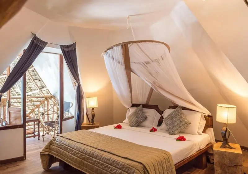 Une chambre lumineuse avec un lit à baldaquin et une vue sur un espace extérieur.
